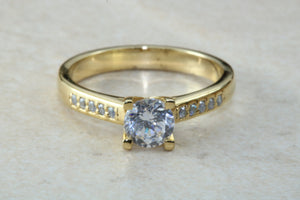 One carat Forever One grade Charled and Colvard Moissanite complemented with natural diamond on the sides of this beautiful 18ct gold ring
