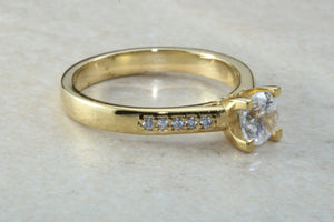 One carat Forever One grade Charled and Colvard Moissanite complemented with natural diamond on the sides of this beautiful 18ct gold ring